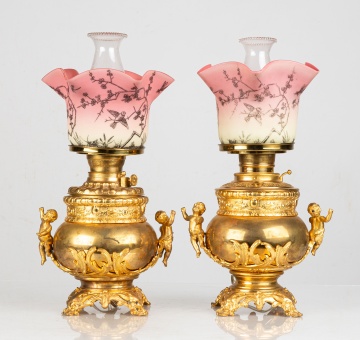 Two Similar Cupid Newel Post Oil Lamps with Burmese Shades